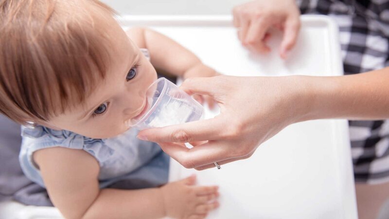 mom-helping-baby-to-drink-in-cup