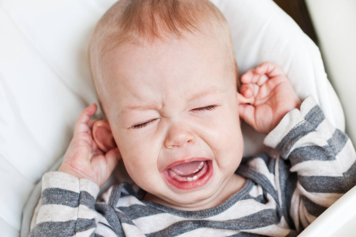 A toddler pulling at his ears in pain
