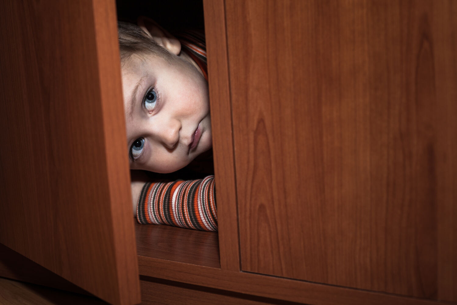 A toddler hiding in fear