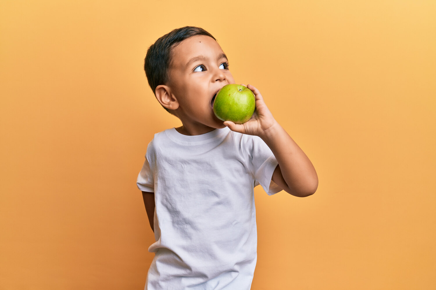 Skinny toddler eating apple