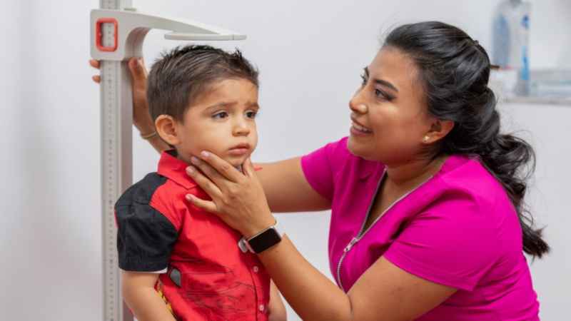 women measuring the height of toddler